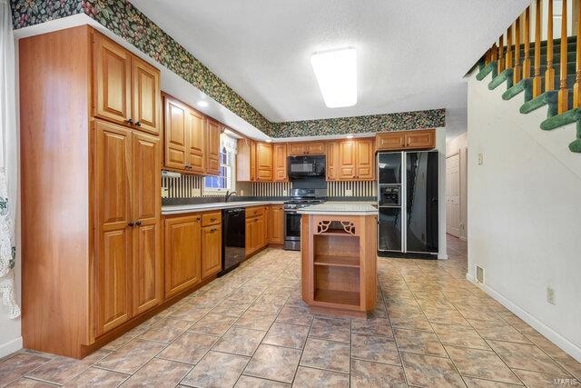 kitchen featuring sink, a center island, and black appliances