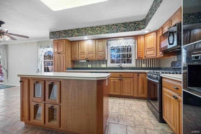 kitchen with ceiling fan, a center island, black appliances, and a textured ceiling