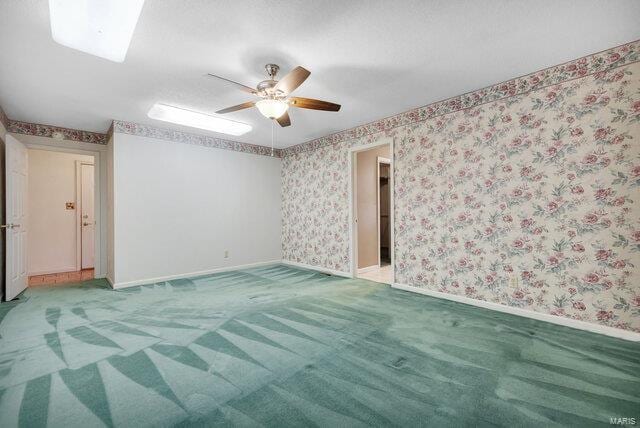 unfurnished room with ceiling fan and carpet