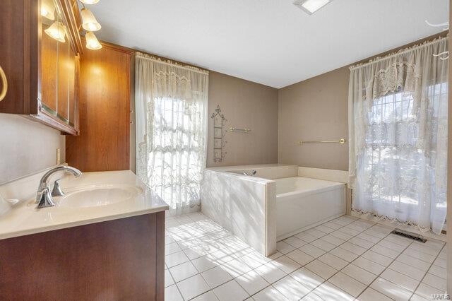 bathroom with tile patterned floors, a washtub, and vanity