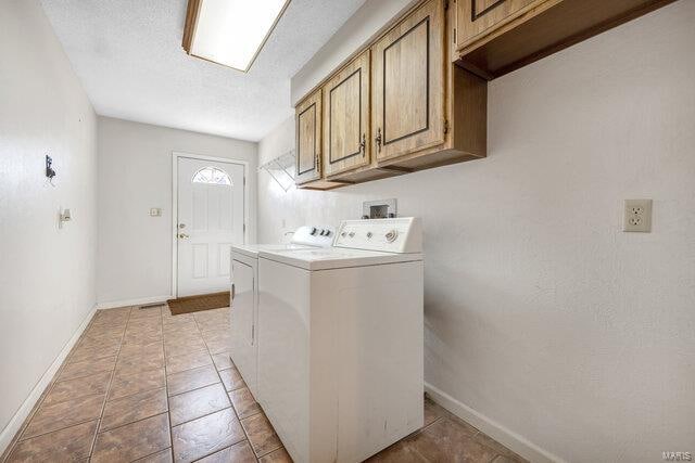 clothes washing area with cabinets, independent washer and dryer, and a textured ceiling