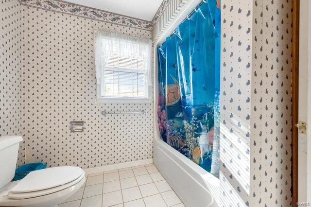 bathroom featuring tile patterned floors, toilet, and shower / bathtub combination with curtain