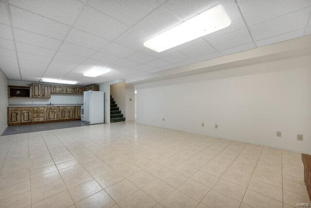 interior space with a paneled ceiling and white fridge