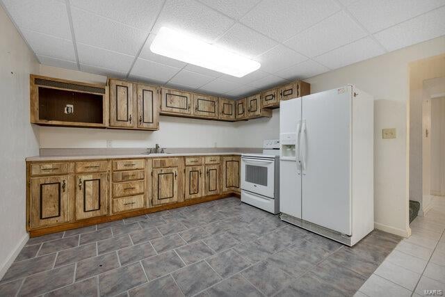 kitchen featuring a drop ceiling, white appliances, and sink