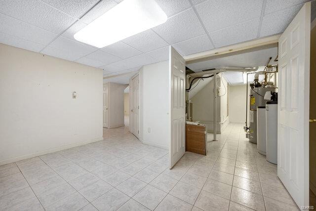 interior space with a paneled ceiling and water heater