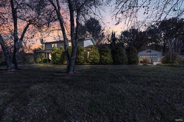 yard at dusk with an outdoor structure and a garage