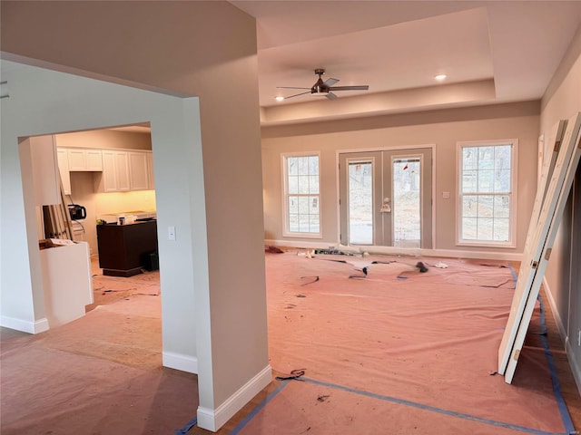 entryway with a raised ceiling, ceiling fan, and french doors