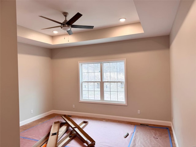 empty room featuring a tray ceiling and ceiling fan