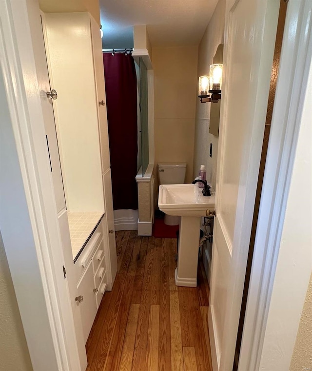 bathroom featuring wood-type flooring, toilet, and sink