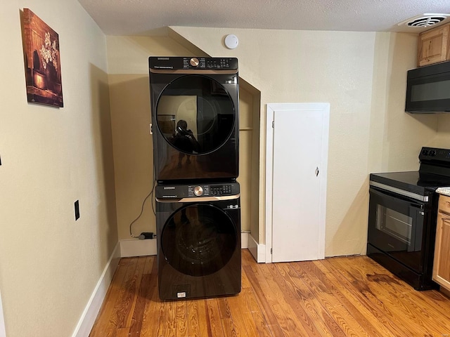 laundry room with light hardwood / wood-style floors, a textured ceiling, and stacked washer and clothes dryer