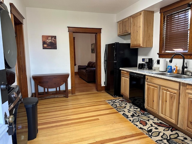 kitchen featuring black appliances, light hardwood / wood-style floors, and sink