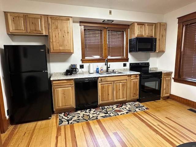 kitchen with sink, light stone counters, light hardwood / wood-style flooring, and black appliances