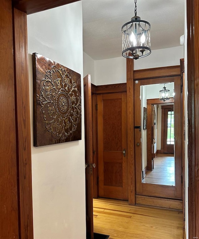 hall with light hardwood / wood-style flooring, french doors, and an inviting chandelier