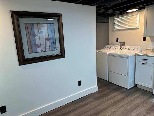 clothes washing area with cabinets, washer and clothes dryer, and dark wood-type flooring