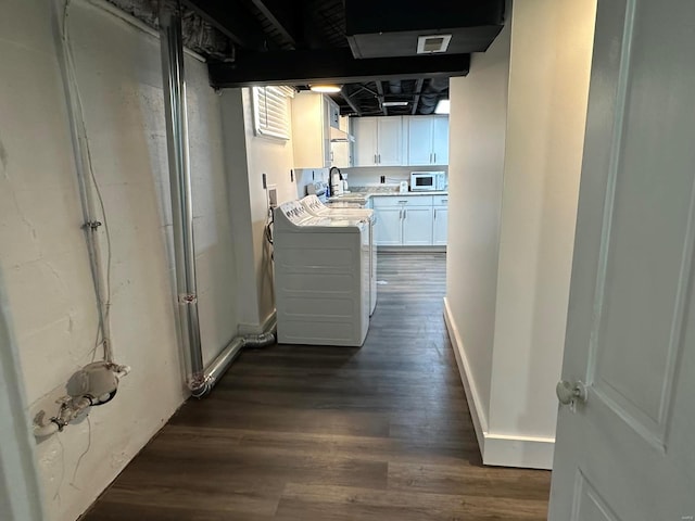 kitchen featuring white microwave, sink, separate washer and dryer, dark hardwood / wood-style flooring, and white cabinetry