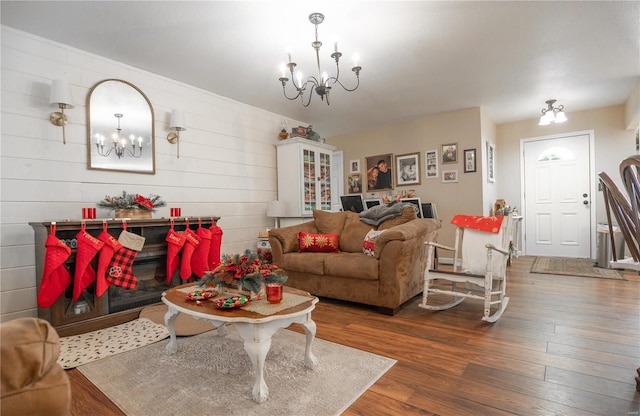 living room featuring wood walls, an inviting chandelier, and hardwood / wood-style flooring