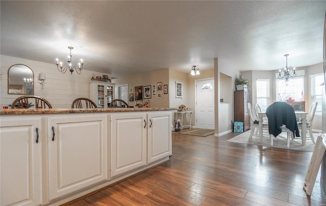 kitchen featuring white cabinets, an inviting chandelier, hanging light fixtures, and dark wood-type flooring