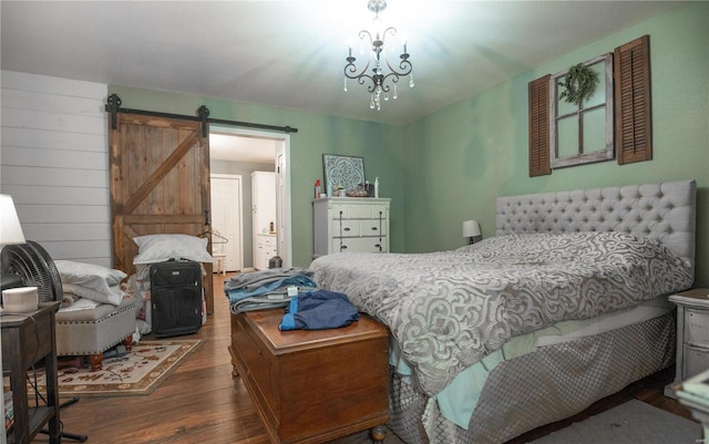 bedroom with a barn door, an inviting chandelier, and dark wood-type flooring