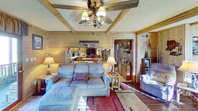 tiled living room with wood walls, ceiling fan, beam ceiling, and a textured ceiling