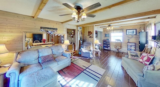 living room with beam ceiling, ceiling fan, dark hardwood / wood-style flooring, wood walls, and a textured ceiling