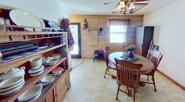 dining room featuring ceiling fan and wood walls