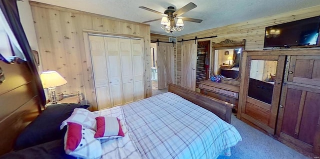 bedroom with carpet flooring, two closets, ceiling fan, wooden walls, and a barn door