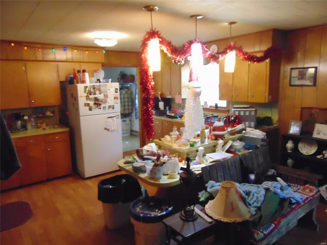 kitchen featuring wood walls, pendant lighting, light wood-type flooring, and white refrigerator