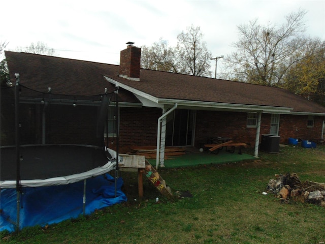 rear view of house featuring a yard and a trampoline