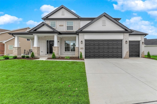 view of front of home featuring covered porch, a garage, and a front lawn