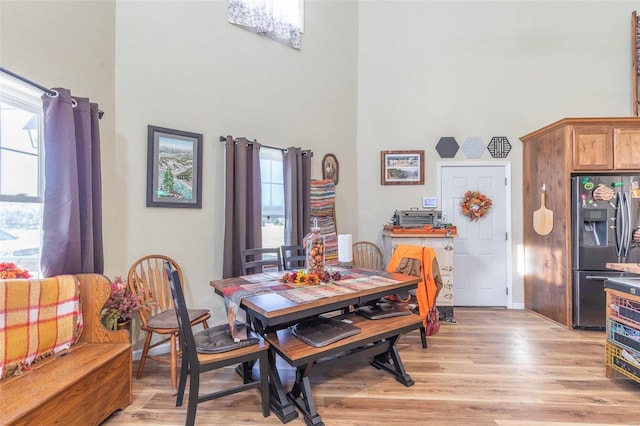 dining space with a towering ceiling and light wood-type flooring