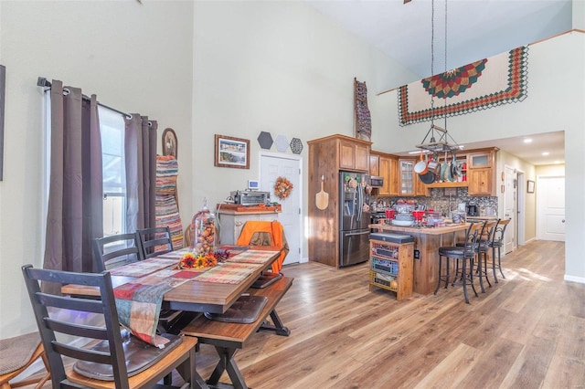 dining area featuring a towering ceiling and light hardwood / wood-style flooring