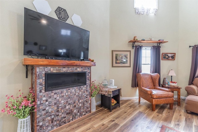 living room featuring a tiled fireplace, light hardwood / wood-style floors, and a notable chandelier