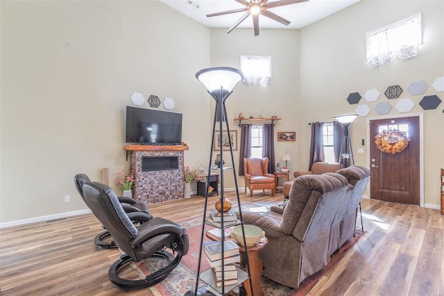 living room featuring hardwood / wood-style floors, ceiling fan, and a fireplace