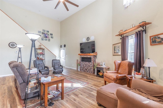 living room featuring a high ceiling, light hardwood / wood-style floors, and ceiling fan