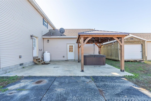 view of patio / terrace featuring a gazebo, an outbuilding, and a hot tub