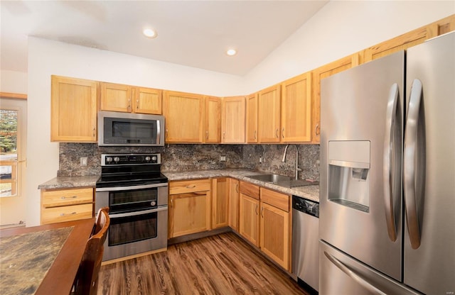 kitchen with sink, vaulted ceiling, dark hardwood / wood-style floors, tasteful backsplash, and stainless steel appliances