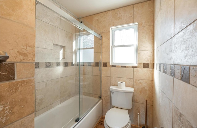 bathroom featuring toilet, tile walls, and enclosed tub / shower combo