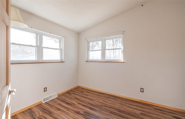 empty room featuring a textured ceiling, dark wood-type flooring, and lofted ceiling