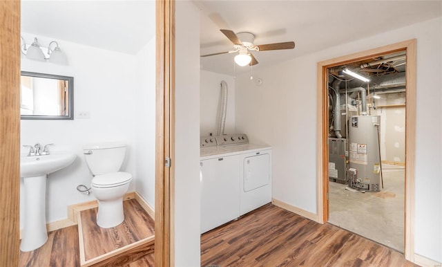 bathroom featuring gas water heater, ceiling fan, separate washer and dryer, hardwood / wood-style flooring, and toilet