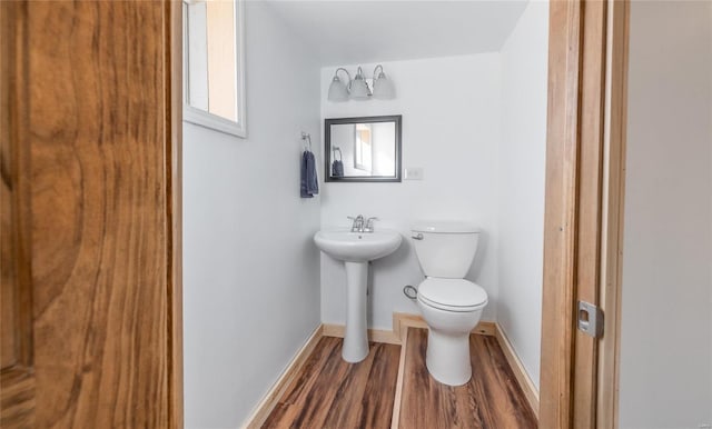 bathroom featuring wood-type flooring, toilet, and sink