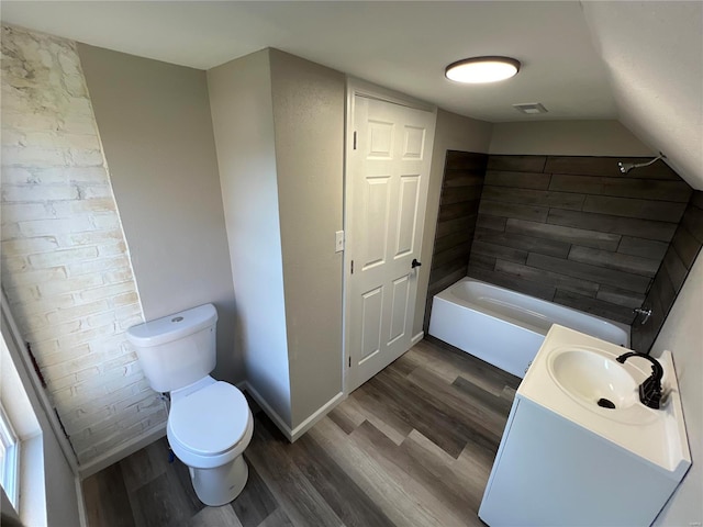 bathroom with wood-type flooring, toilet, a bath, and vanity