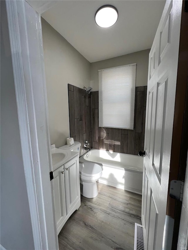 full bathroom featuring hardwood / wood-style flooring, shower / bathing tub combination, vanity, and toilet