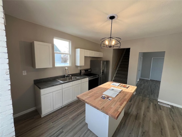 kitchen featuring pendant lighting, white cabinets, butcher block counters, sink, and range with electric stovetop