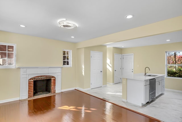 unfurnished living room featuring a fireplace, sink, and light hardwood / wood-style flooring