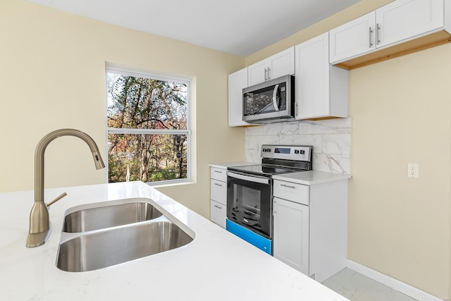 kitchen with backsplash, white cabinetry, sink, and stainless steel appliances