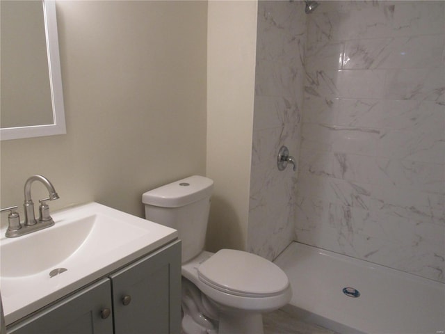 bathroom featuring tiled shower, vanity, and toilet