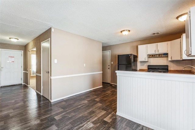 kitchen with stove, white cabinets, black refrigerator, a textured ceiling, and dark hardwood / wood-style flooring