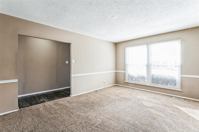 spare room featuring dark colored carpet and a textured ceiling