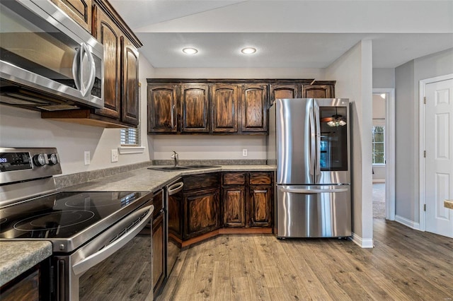 kitchen with dark brown cabinetry, sink, appliances with stainless steel finishes, and light hardwood / wood-style flooring