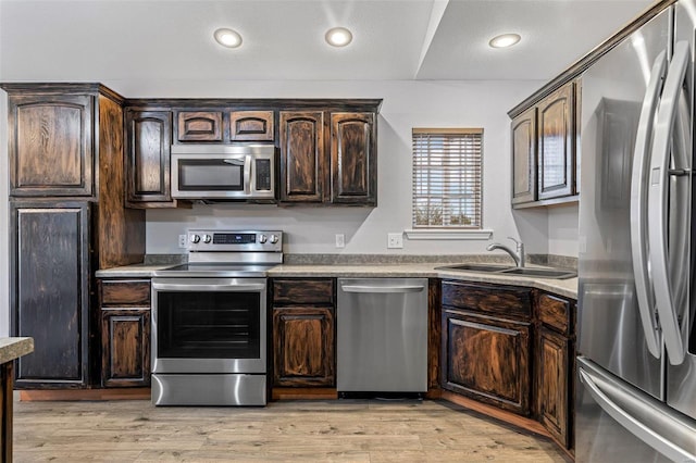 kitchen featuring dark brown cabinetry, sink, stainless steel appliances, and light hardwood / wood-style floors